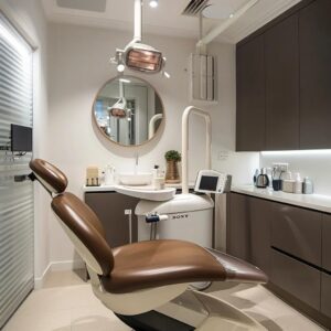 a modern dental clinic in sandgate features a sleek treatment room with advanced orthodontic equipment, highlighting a confident patient admiring their newly straightened smile in a large mirror.