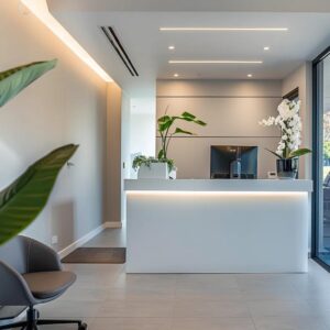 a modern dental office in sandgate, featuring a sleek reception area with a welcoming atmosphere, where an expert practitioner discusses affordable dental services with a patient, illuminated by soft, professional lighting.